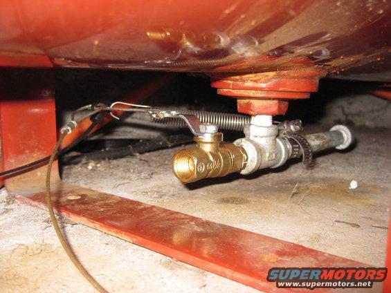 close-up of brass drain valve and metal pipe attached to red tank