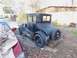 1909 Ford Model T - A vintage black coupe sits in a driveway covered in fallen leaves, with a spare tire mounted on the rear.