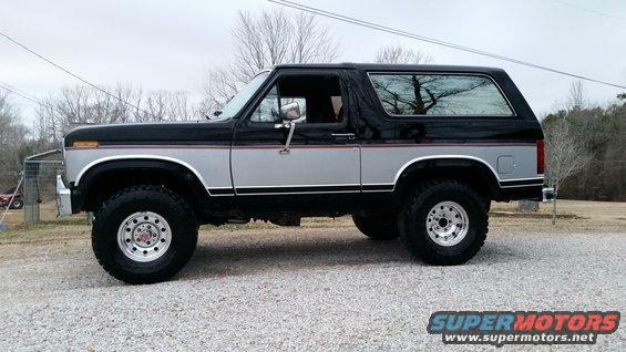 Two-tone black and silver Ford Bronco with aftermarket wheels parked on a gravel lot