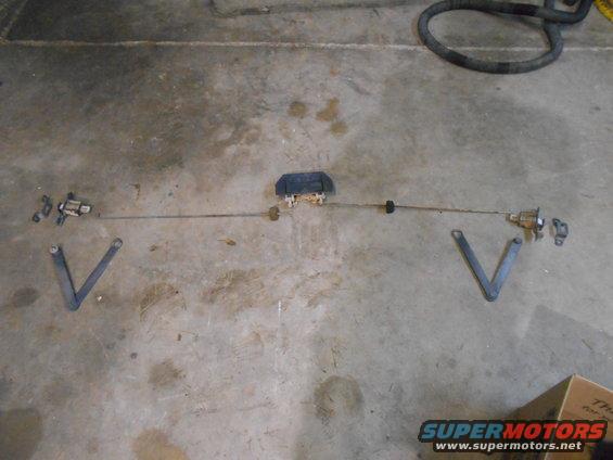 Door lock actuator linkage assembly laid out on concrete floor