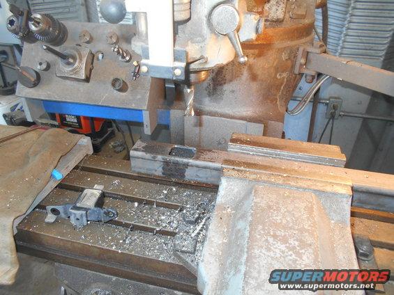 Milling machine with drill bit, metal shavings, and a part on the table