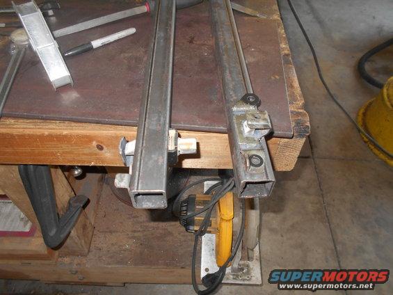 Metal tubing and brackets clamped to a workbench with tools nearby