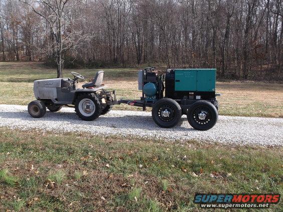 Tractor towing a green generator on a gravel road
