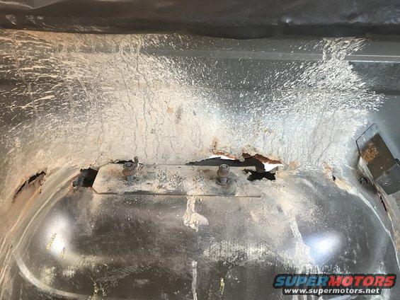 rusted metal with bolts and white residue, likely undercarriage of a vehicle