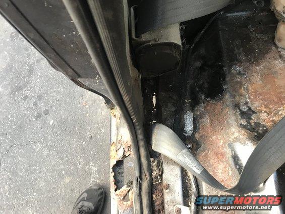 Interior door frame and rusted floor pan with seatbelt