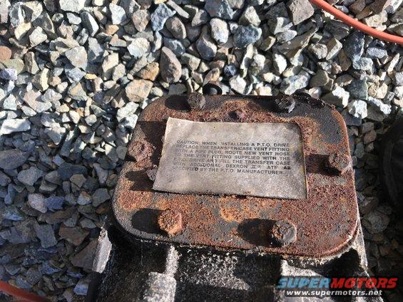 Transfer case part with caution label about PTO drive installation and fluid