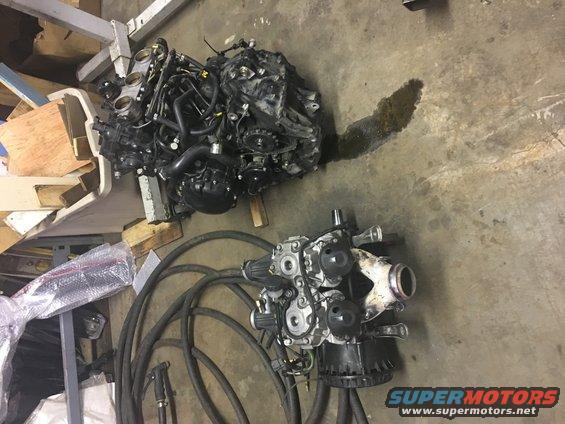 Two disassembled engines and associated parts on a concrete floor