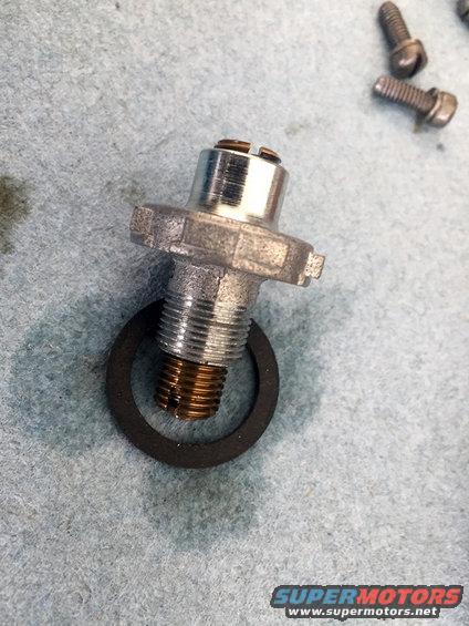 Fuel pressure regulator with gasket and two screws on a gray surface