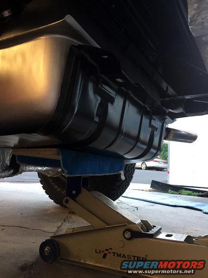 Fuel tank and exhaust pipe supported by a jack and wooden blocks under a vehicle