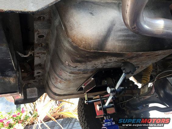 Undercarriage of a vehicle being supported by a jack. Visible text '76038'