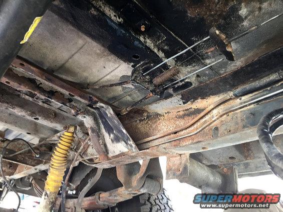 undercarriage of a vehicle with rust and yellow shock absorber