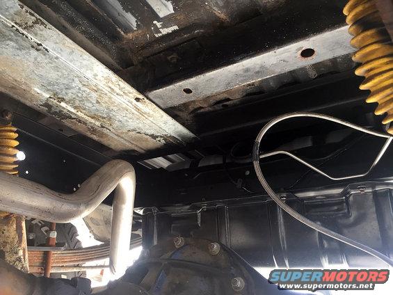 Undercarriage of a vehicle with yellow springs, exhaust pipe, and differential