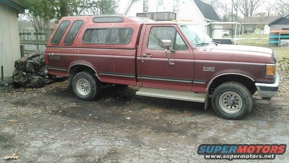 Maroon 1991 Ford F-150 with a red camper shell, seen from the side at a 3/4 front angle