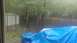 2006 Honda RANCHER - A backyard is submerged in floodwaters, with a shed and a blue tarp visible.