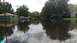 2006 Honda RANCHER - Suburban street flooded with water, with multiple vehicles parked on the side.