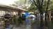 2006 Honda RANCHER - Backyard flooded with debris and a trailer visible near the house.