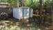 2006 Honda RANCHER - A backyard is submerged in floodwaters, with a metal shed and a stack of firewood visible.