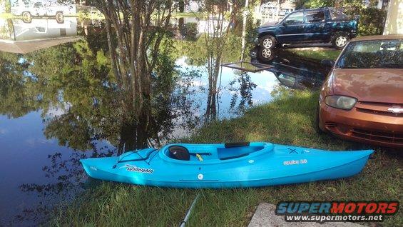 Blue kayak on grass near flooded area with a pickup truck and sedan
