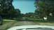 2006 Honda RANCHER - Driving down a tree-lined road with houses on either side and two cars in the distance.