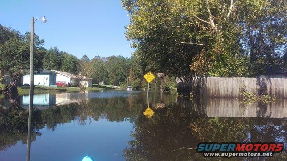 Flooded street with a yellow warning sign reflecting in the water