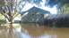 2006 Honda RANCHER - A car sits in a flooded yard next to a house and wooden fence.