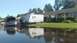 2006 Honda RANCHER - A dark-colored truck with its hood open sits partially submerged in floodwaters next to a house and a trailer.