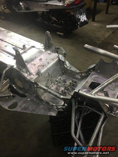 Snowmobile chassis in shop, another snowmobile in background with skull sticker