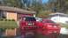 2006 Honda RANCHER - Two red vehicles are partially submerged in floodwaters in front of a residential property.