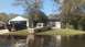 2006 Honda RANCHER - A tan pickup truck sits on a flooded lawn next to a house, with another black pickup truck visible in the driveway.