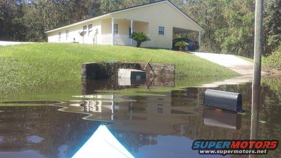 Flooded street in front of a house, with mailboxes submerged