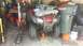 2006 Honda RANCHER - Red ATV, possibly a 2006 Honda RANCHER, is raised on a hydraulic jack in a cluttered garage.