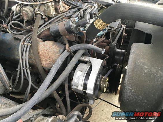 Close-up of a vehicle's engine bay, showing belts, hoses, and alternator