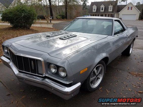 1976 Ford Ranchero with hood scoops and aftermarket wheels, parked in a driveway