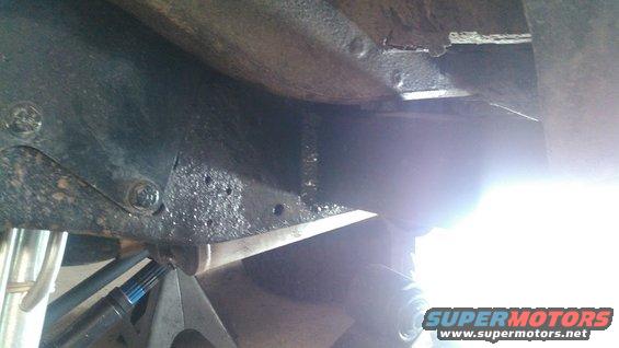 Vehicle frame and suspension parts on jack stands, with a bright light flare obscuring details