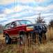 1995 Ford Bronco - Red 1995 Ford Bronco with aftermarket bumper and winch in a field.