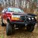 1995 Ford Bronco - This red Ford Bronco features a custom winch bumper and off-road tires, suggesting a model year earlier than 1995.