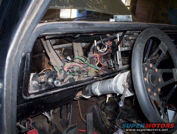 Car interior showing exposed dashboard wiring and steering wheel