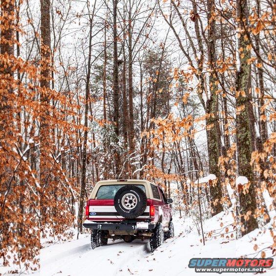 Red and white 1995 Ford Bronco rear view in snowy woods