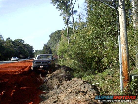Brown Ford F-Series truck off-road on dirt mound, front grille visible