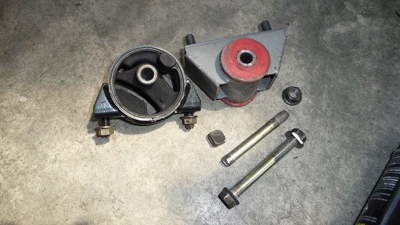 Two engine mounts and assorted bolts on a concrete surface