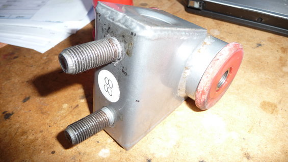 metal automotive part with two threaded studs and a red bushing