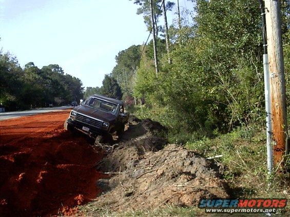1985 Ford Bronco stuck in a dirt embankment next to a road