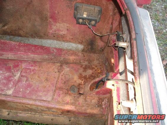 rusted red car trunk interior with wiring and a black electrical box