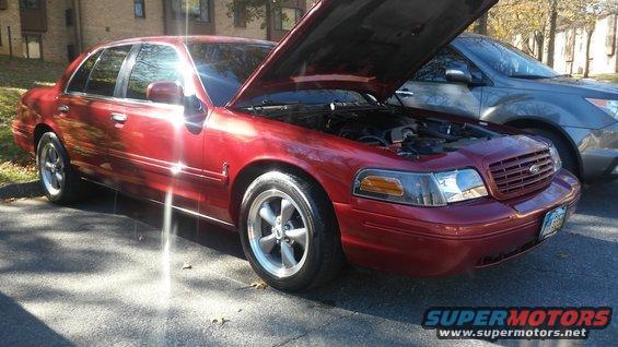 Red 2003 Ford Crown Victoria with hood open, parked next to a grey SUV