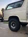 1981 Ford Bronco - Rear view of a white 1981 Ford Bronco, showing its quarter panel and large BFGoodrich tires.
