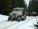 1990 Ford Bronco - A vintage Willys Jeep navigates a snowy trail, with other vehicles following in the background.