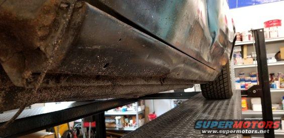 car's rusty rocker panel and undercarriage on a lift
