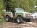 1990 Ford Bronco - Off-road Bronco navigating a wet, muddy path through trees.