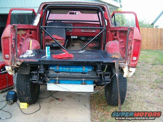 Red 1979 Ford Bronco rear view with open doors and roll cage