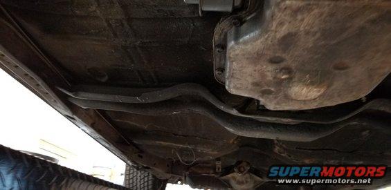 Underside of a vehicle showing exhaust pipe, crossmember and floor pan